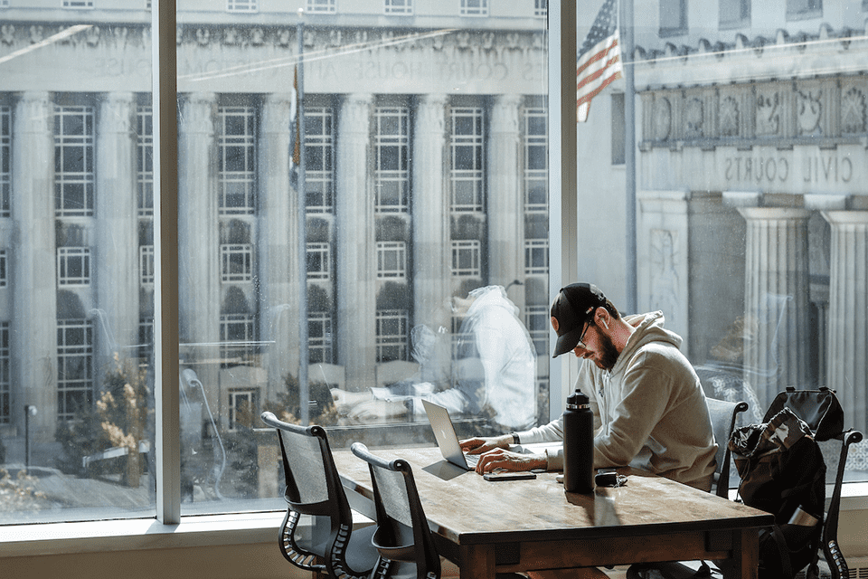 Male student studies at desk in library. Civil courts building can be seen outside the window.